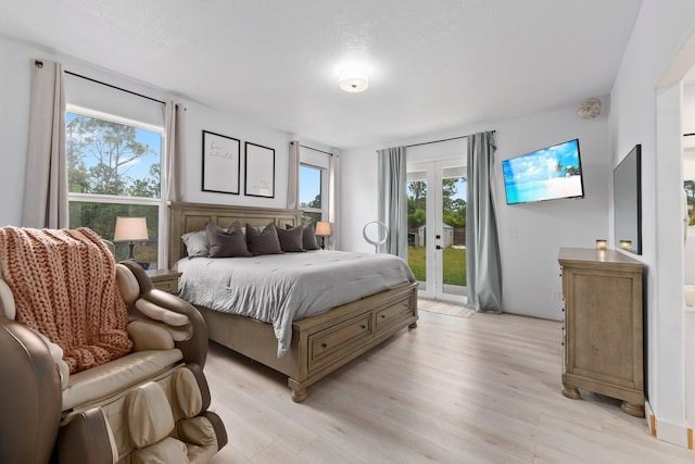 bedroom featuring light wood-type flooring, french doors, access to outside, and multiple windows