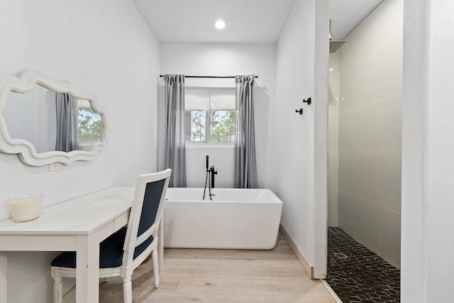 bathroom with a wealth of natural light, hardwood / wood-style floors, and plus walk in shower