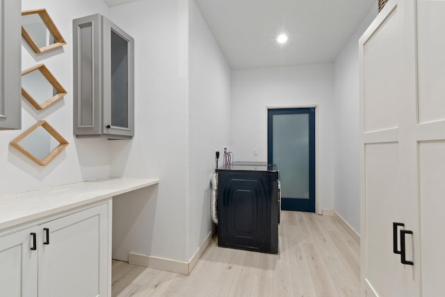 washroom with cabinets, hookup for a washing machine, and light hardwood / wood-style floors