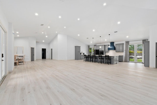 living room featuring french doors, high vaulted ceiling, and light hardwood / wood-style flooring