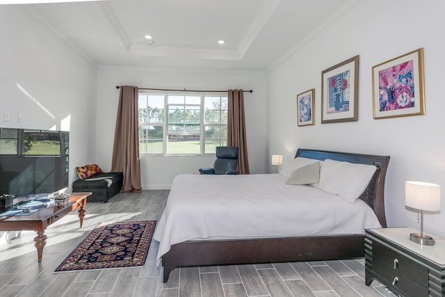 bedroom with a raised ceiling, crown molding, and light hardwood / wood-style flooring