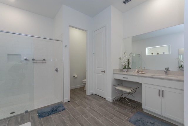 bathroom with tiled shower, vanity, and toilet