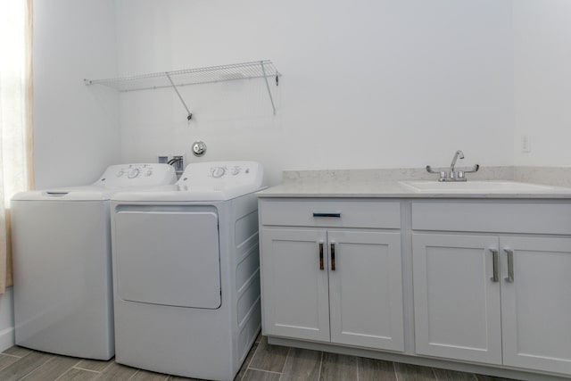 laundry room featuring cabinets, washing machine and dryer, sink, and light hardwood / wood-style flooring