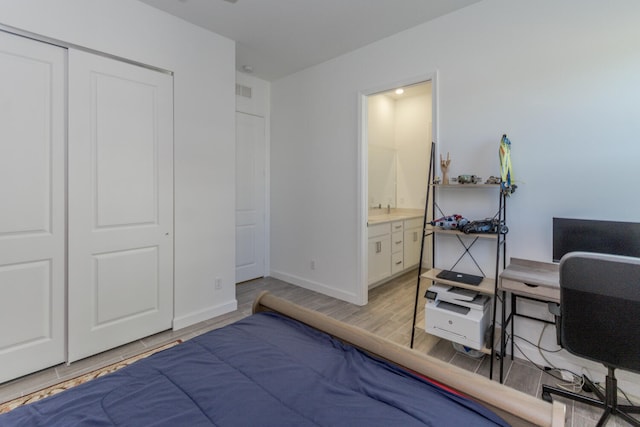 bedroom with light wood-type flooring, ensuite bathroom, and a closet