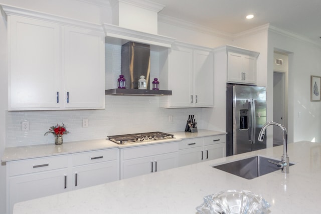 kitchen featuring light stone countertops, stainless steel appliances, wall chimney range hood, sink, and white cabinets