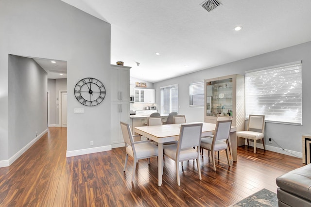 dining area with dark hardwood / wood-style flooring and vaulted ceiling