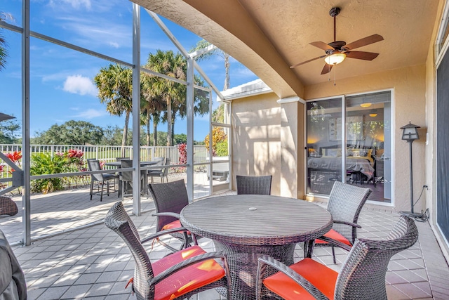 view of patio featuring ceiling fan and glass enclosure