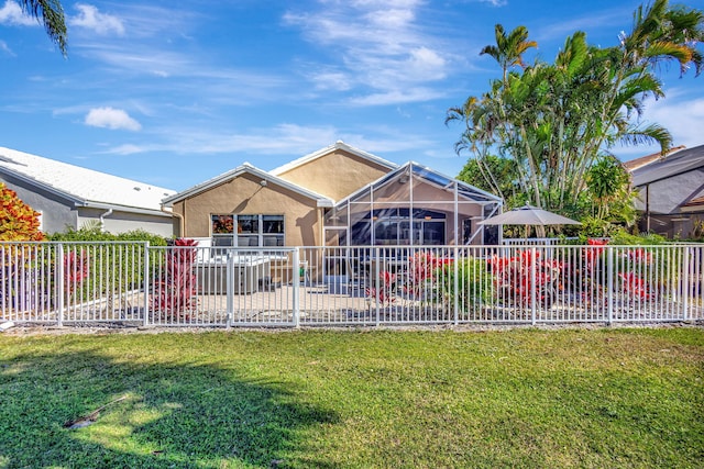 rear view of property featuring a lawn and glass enclosure