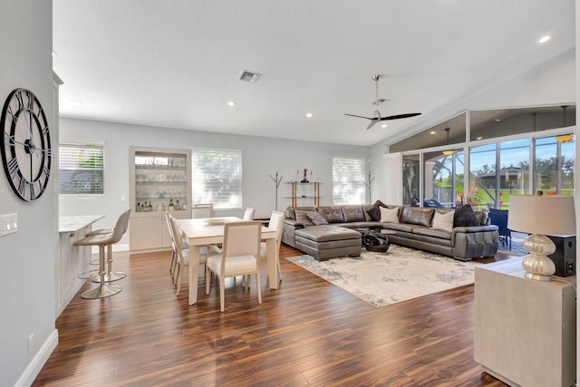 living room with a wealth of natural light, ceiling fan, dark wood-type flooring, and lofted ceiling