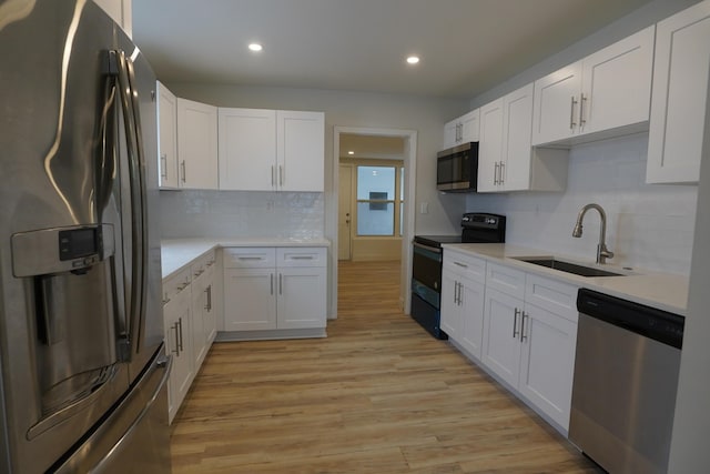 kitchen with white cabinetry, sink, stainless steel appliances, and light hardwood / wood-style floors