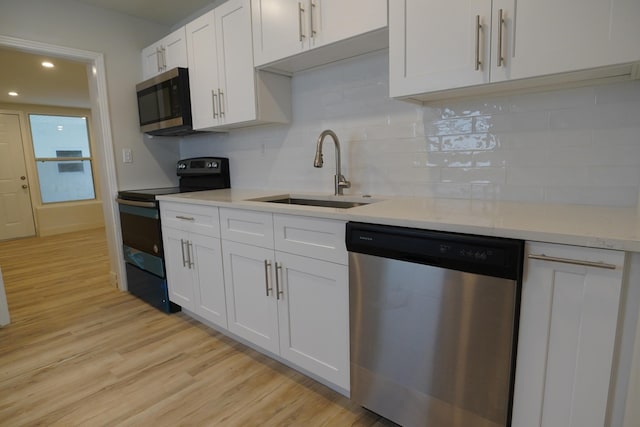 kitchen featuring sink, decorative backsplash, light wood-type flooring, appliances with stainless steel finishes, and white cabinetry