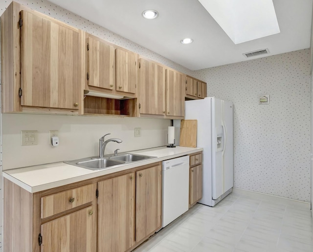 kitchen featuring a skylight, sink, light brown cabinetry, and white appliances