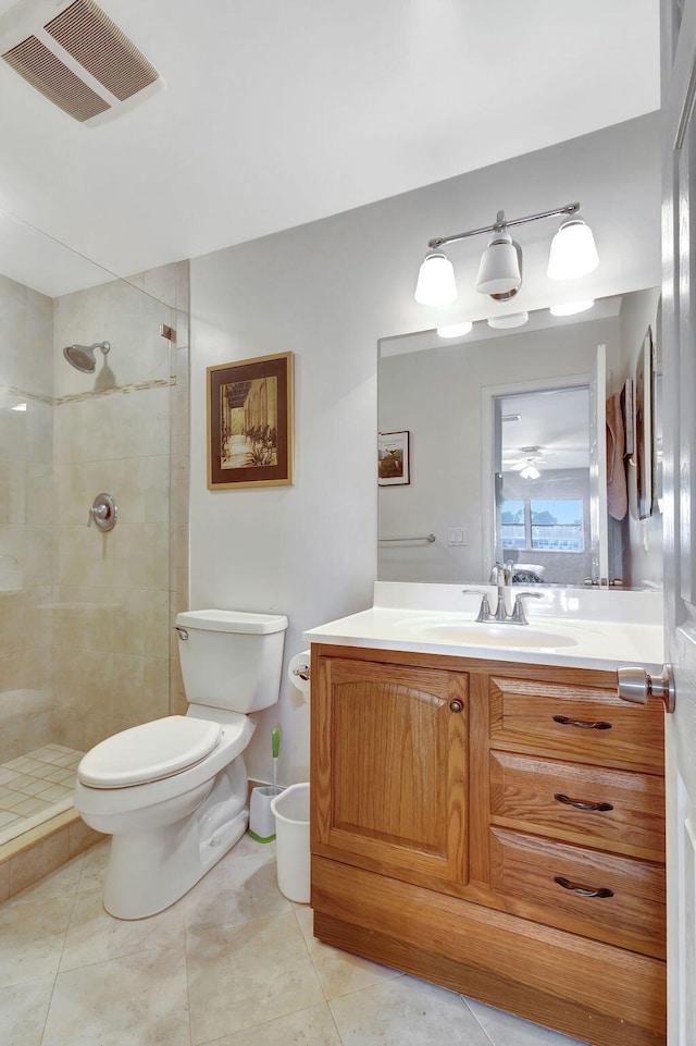 bathroom with tile patterned flooring, a tile shower, vanity, and toilet