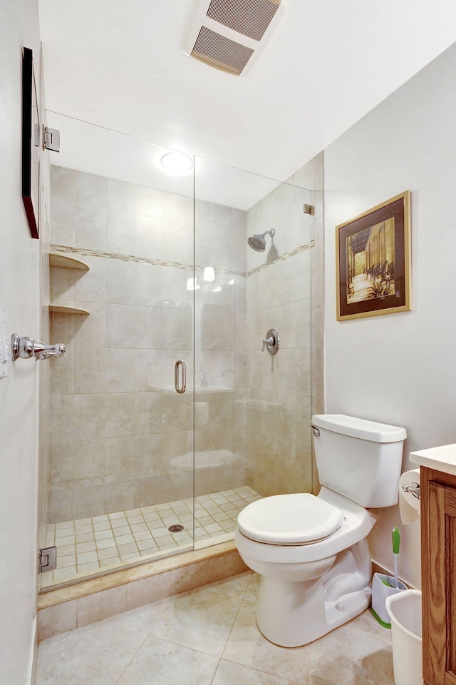 bathroom with tile patterned flooring, vanity, a shower with shower door, and toilet