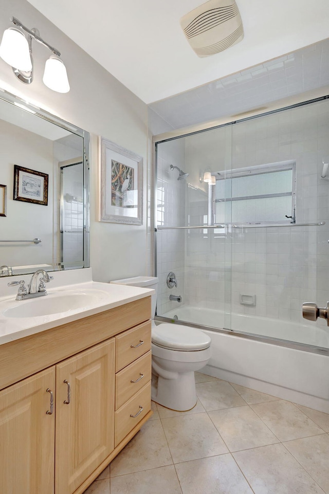 full bathroom with shower / bath combination with glass door, vanity, tile patterned flooring, and toilet