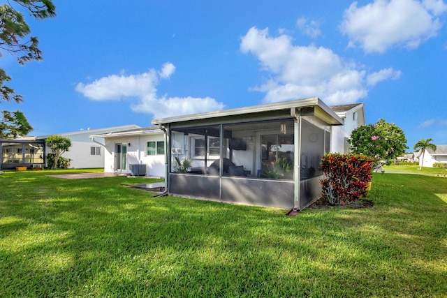 back of house featuring central air condition unit, a sunroom, and a lawn