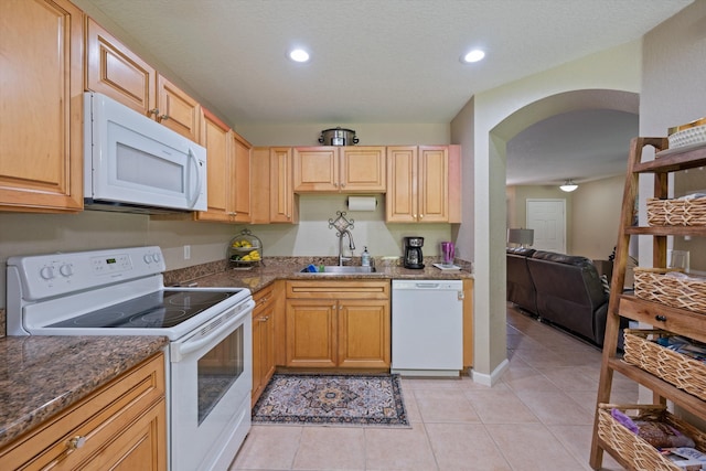 kitchen with light tile patterned floors, recessed lighting, arched walkways, white appliances, and a sink