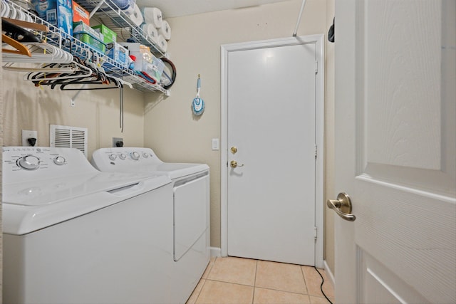 clothes washing area with light tile patterned floors, laundry area, and washing machine and clothes dryer
