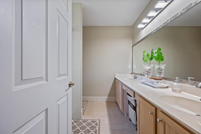 bathroom with tile patterned floors, double vanity, baseboards, and a sink