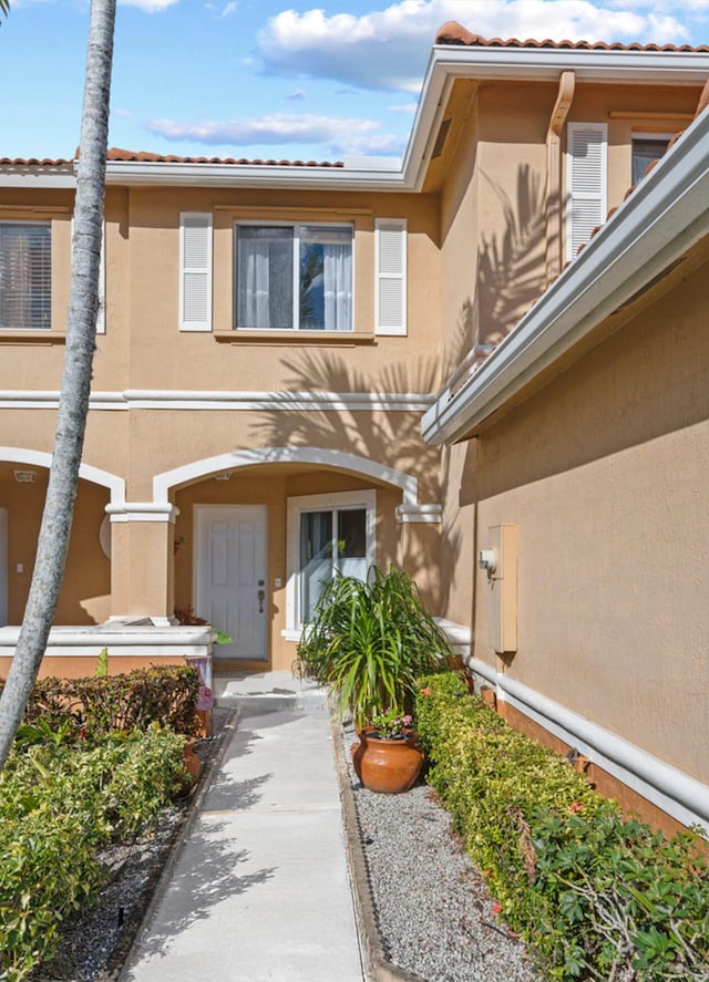 property entrance featuring stucco siding and a tile roof