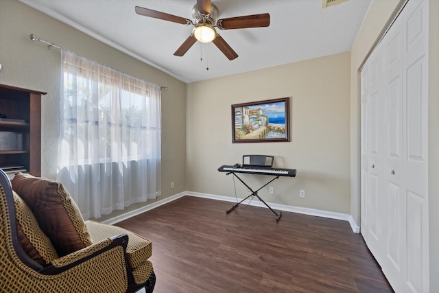 sitting room featuring baseboards, dark wood-style floors, and a ceiling fan