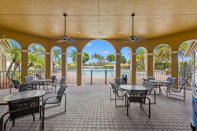 view of patio / terrace with ceiling fan, a community pool, and a water view