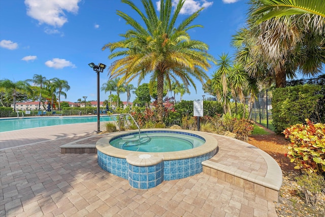 community pool with a patio area, a community hot tub, and fence