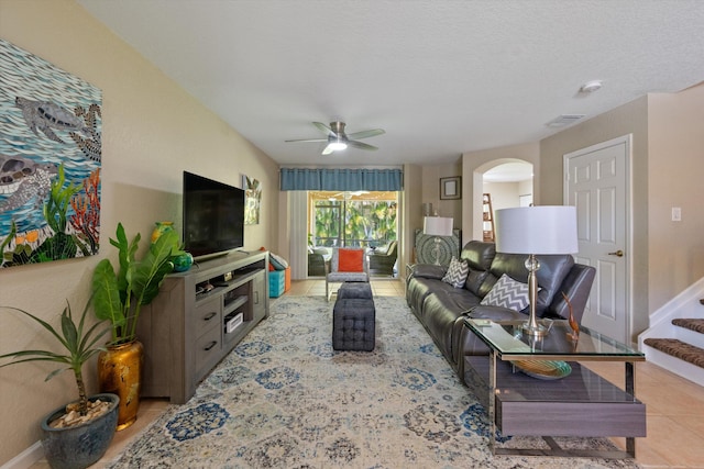 living area with light tile patterned floors, baseboards, arched walkways, and ceiling fan