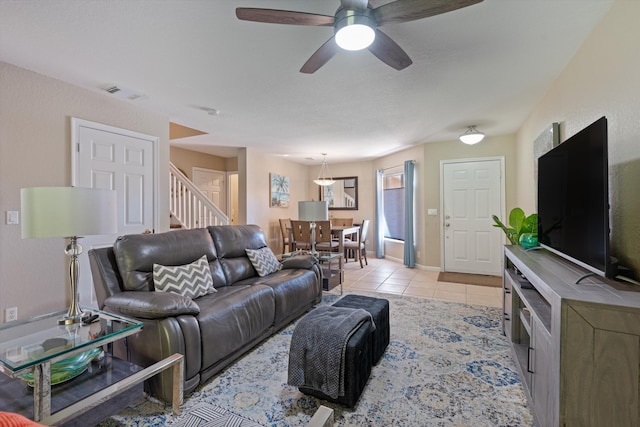 living room featuring visible vents, a ceiling fan, stairway, light tile patterned flooring, and baseboards