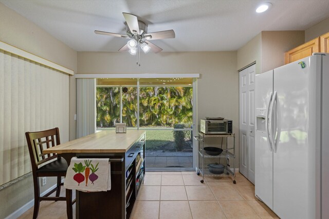 kitchen featuring light tile patterned floors, a toaster, ceiling fan, butcher block countertops, and white refrigerator with ice dispenser