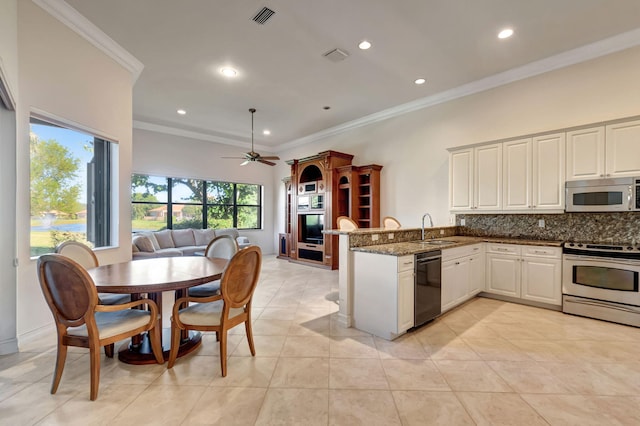 kitchen with dark stone counters, crown molding, decorative backsplash, appliances with stainless steel finishes, and kitchen peninsula