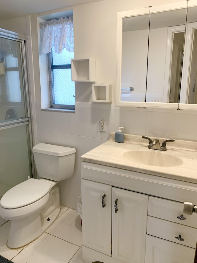 bathroom with vanity, a shower with door, tile walls, tile patterned flooring, and toilet