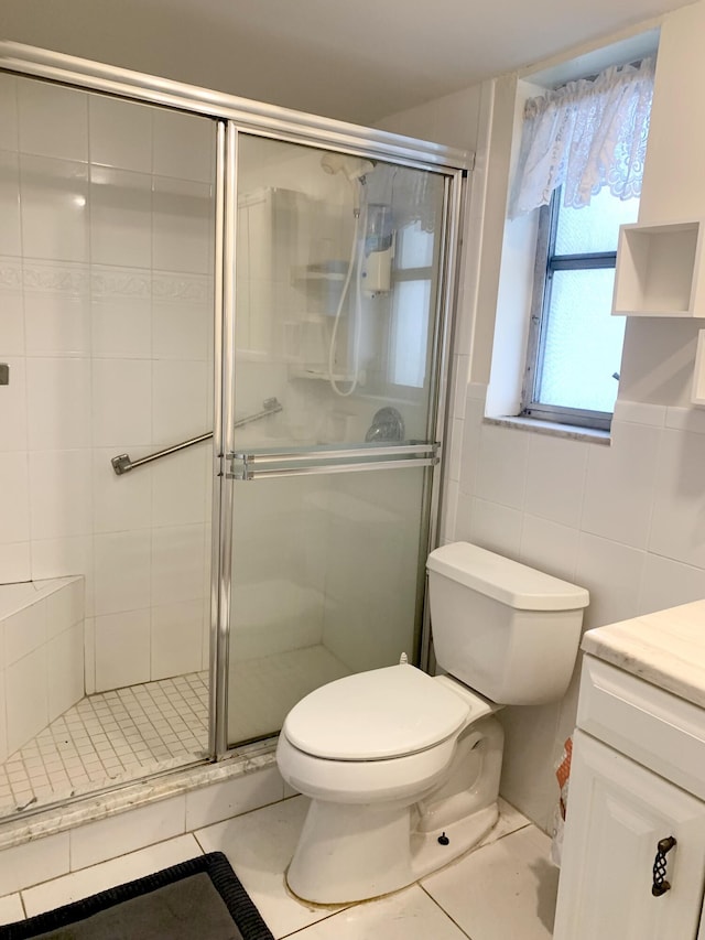 bathroom featuring tile patterned floors, an enclosed shower, vanity, tile walls, and toilet