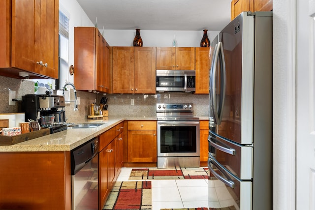 kitchen with light tile patterned flooring, sink, tasteful backsplash, light stone counters, and appliances with stainless steel finishes