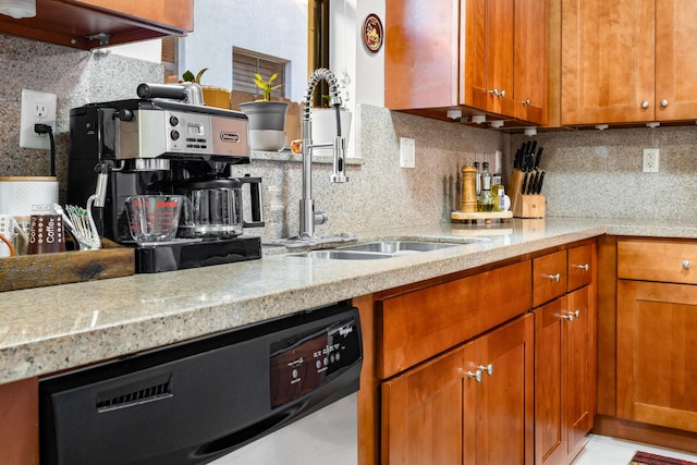 kitchen featuring light stone counters, dishwasher, sink, and decorative backsplash