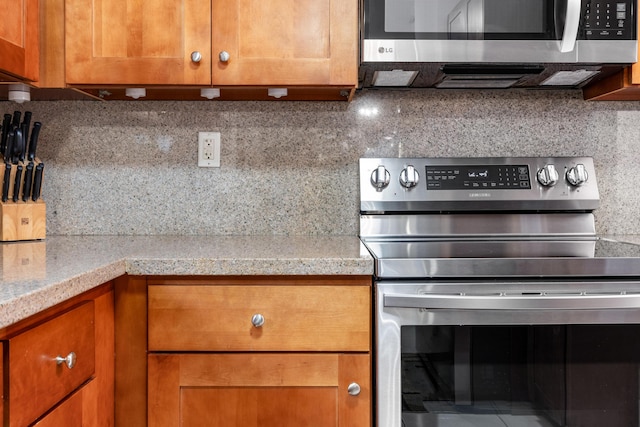 kitchen featuring tasteful backsplash, stainless steel appliances, and light stone countertops