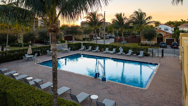 pool at dusk featuring a patio