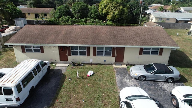 1675 E Breezy Ln, West Palm Beach, FL 33417 - view of front facade featuring fence, stucco siding, roof with shingles, and a front yard