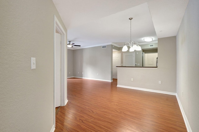 interior space featuring ceiling fan with notable chandelier, hardwood / wood-style flooring, and ornamental molding