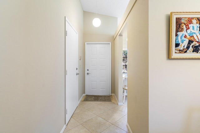 corridor featuring a textured ceiling, light tile patterned floors, and lofted ceiling