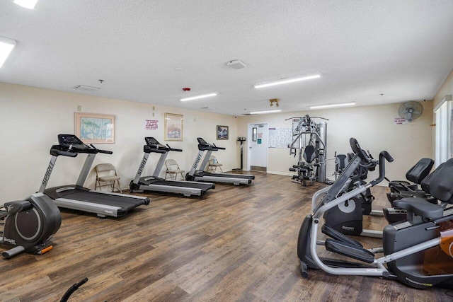 exercise room featuring a textured ceiling and dark hardwood / wood-style flooring