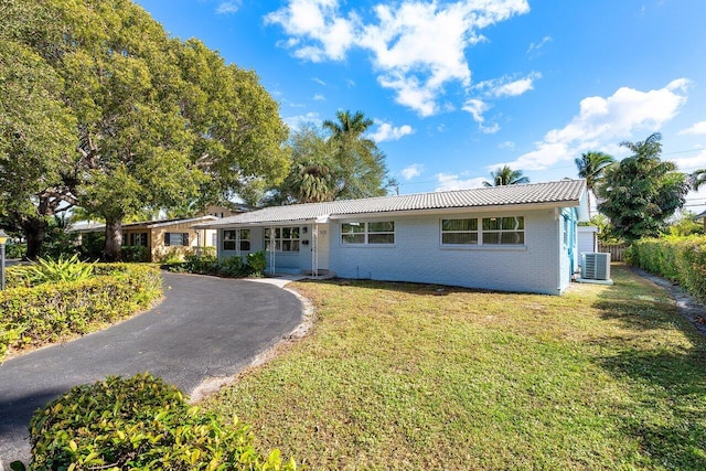 ranch-style house featuring central AC unit and a front lawn