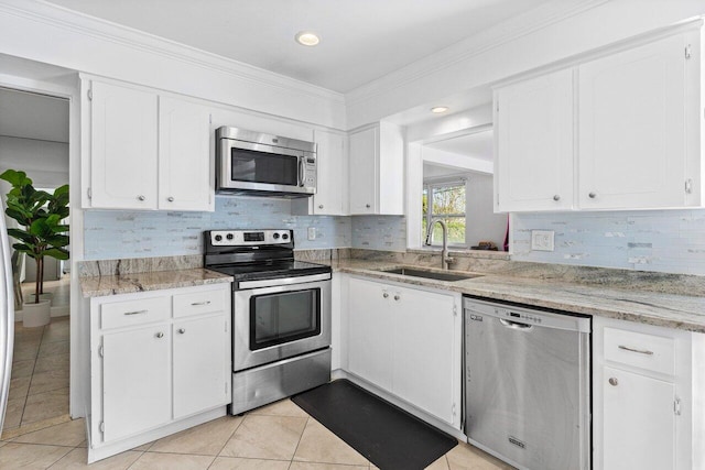 kitchen with white cabinets, sink, light tile patterned floors, ornamental molding, and appliances with stainless steel finishes