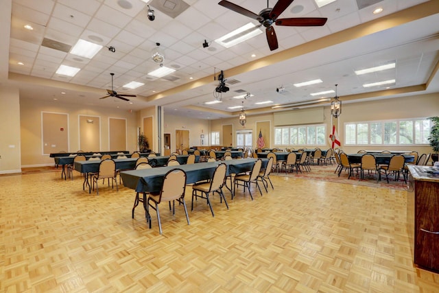 dining space with ceiling fan, a drop ceiling, and light parquet flooring