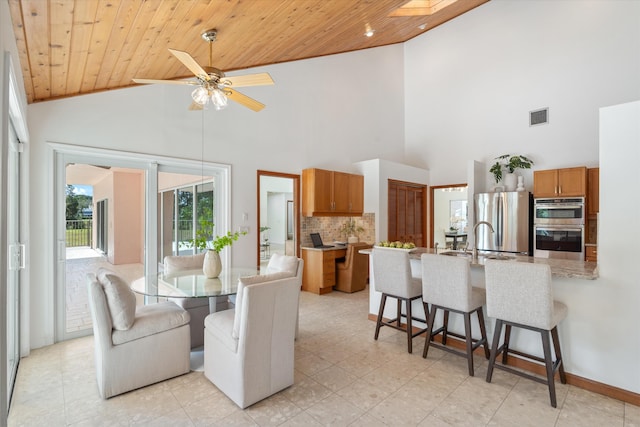 dining area featuring a skylight, high vaulted ceiling, ceiling fan, and wood ceiling