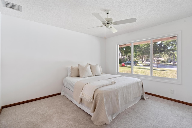 bedroom featuring a textured ceiling, ceiling fan, and light carpet