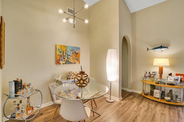 dining space featuring hardwood / wood-style flooring, high vaulted ceiling, and a notable chandelier