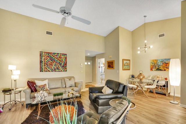 living room featuring hardwood / wood-style flooring, ceiling fan with notable chandelier, and high vaulted ceiling