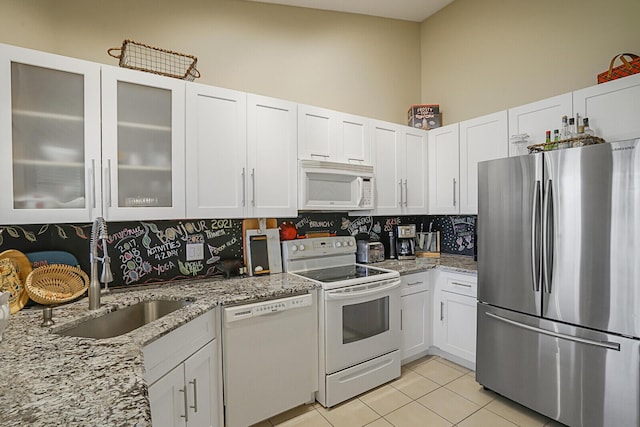 kitchen with light tile patterned flooring, white appliances, white cabinetry, and sink