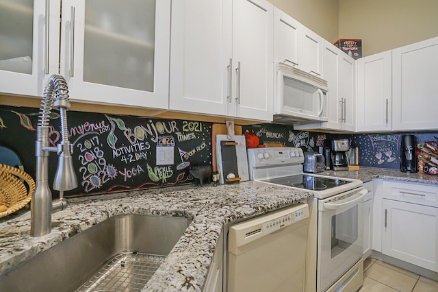 kitchen featuring tasteful backsplash, white appliances, sink, white cabinets, and light tile patterned flooring